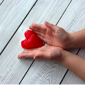 Child hold red glittery slime in the shape of a heart