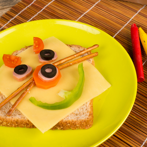 snack food that is kid friendly with a cat face made from veggies and cheese and pretzels