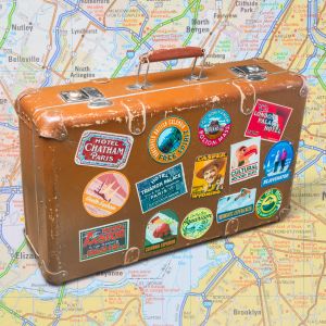 Suitcase with travel stickers on map background