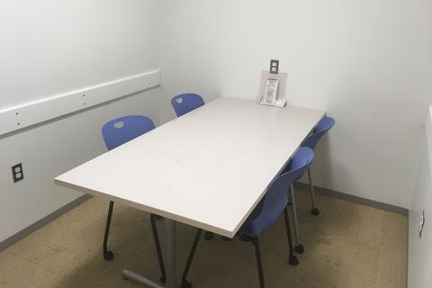 Small study room with rectangular table and seating for four people