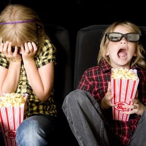 children eating popcorn and watching a movie