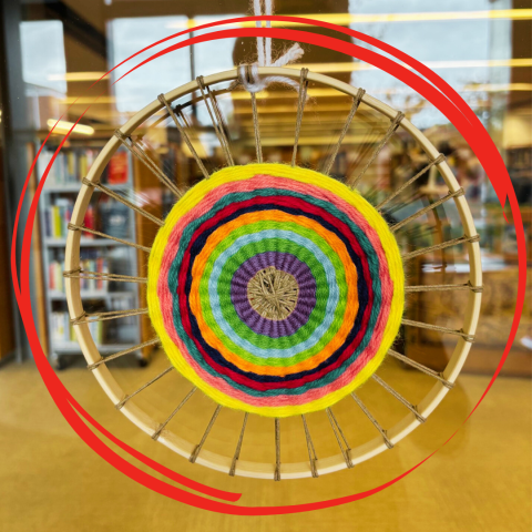 A colorful weaving in the center of a wooden hoop. A red circular graphic surrounds it for emphasis.