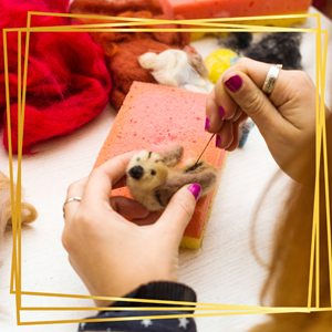 An image of needle felting, a brown bird against a pink foam block.