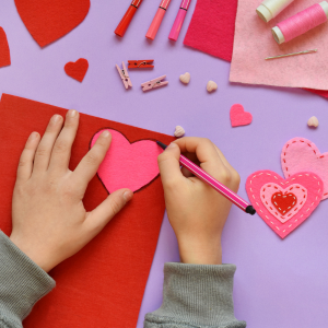 Photo of child's hand tracing heart with craft supplies