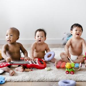 Photo of babies sitting on rug with toys